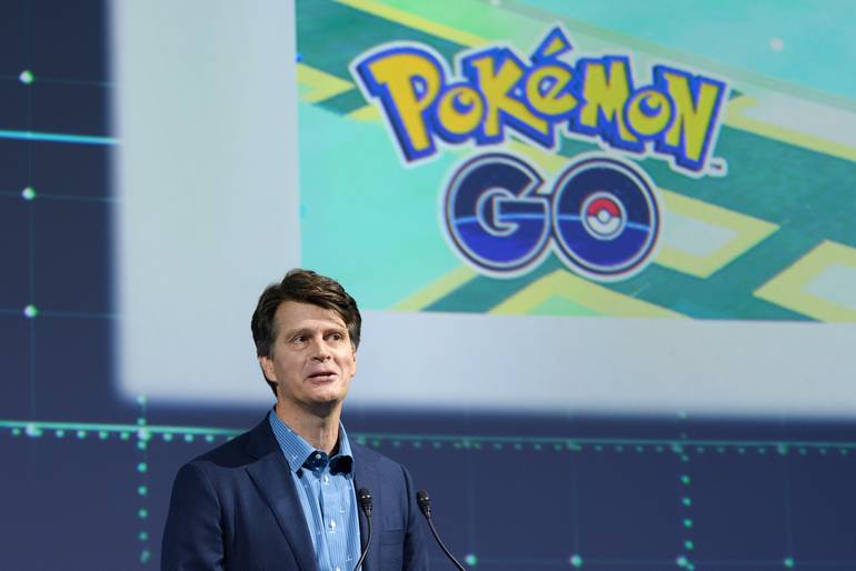 Fotografia mostra o CEO da Niantic, John Hanke, em uma palestra. O executivo se encontra em um palco e, em um telão atrás dele, uma imagem de Pokémon GO é reproduzida. 