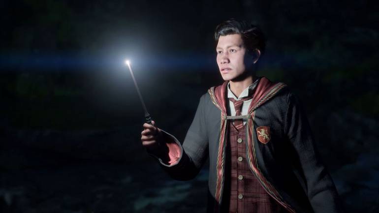 Cena de Hogwarts Legacy mostra um aluno da Grifinória usando sua varinha para acender um local escuro