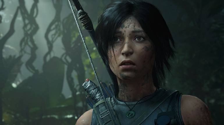 Cena de Shadow of the Tomb Raider mostra Lara Croft com uma feição assustada e lama no rosto. Ela se encontra em uma selva.
