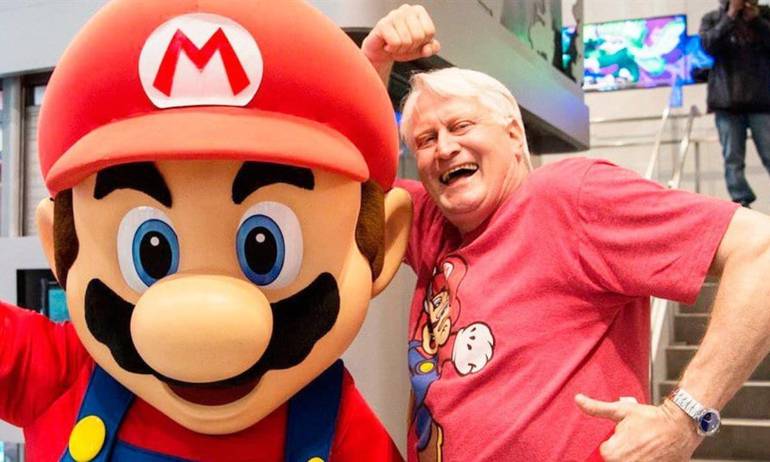 Foto mostra Mario ao lado de Charles Martinet, um senhor branco de cabelos curtos e brancos localizado à direita da imagem