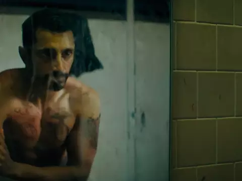 Riz Ahmed se olhando no espelho em Encounter