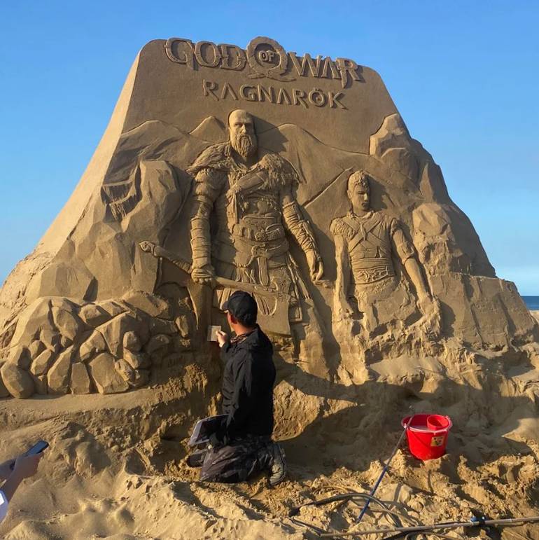 Foto mostra o artista construindo a escultura de areia de God of Wa: Ragnarok